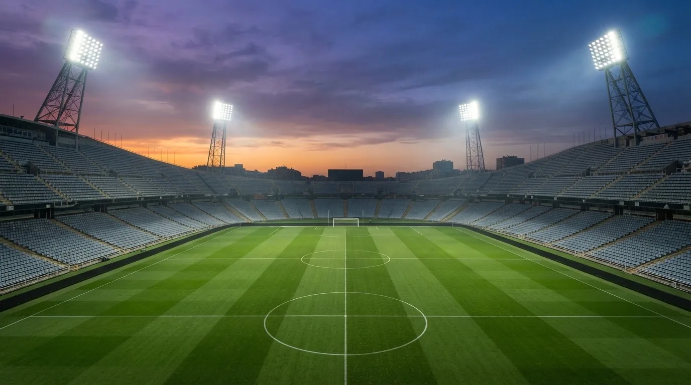Un estadio de fútbol vacío con torres de iluminación al atardecer
