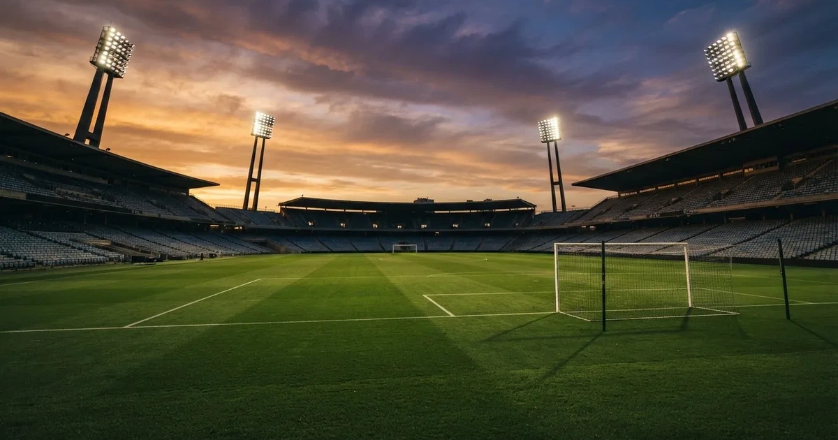 Un estadio de fútbol vacío con torres de iluminación al atardecer