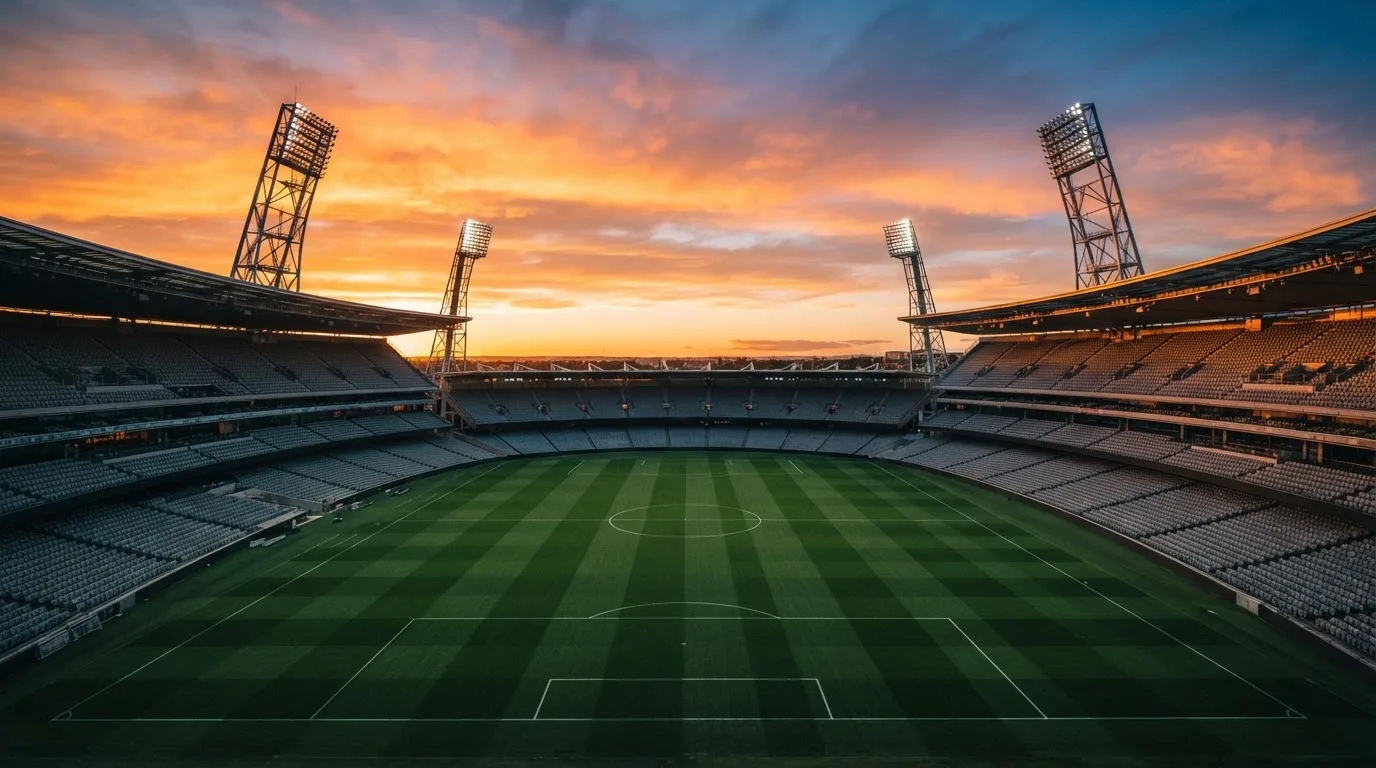 Un estadio de fútbol vacío con torres de iluminación al atardecer