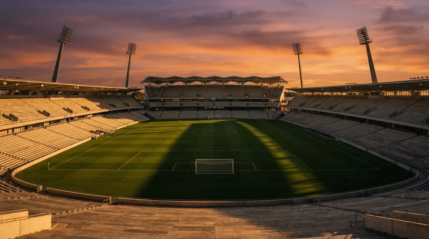 Un estadio de fútbol vacío con torres de iluminación al atardecer