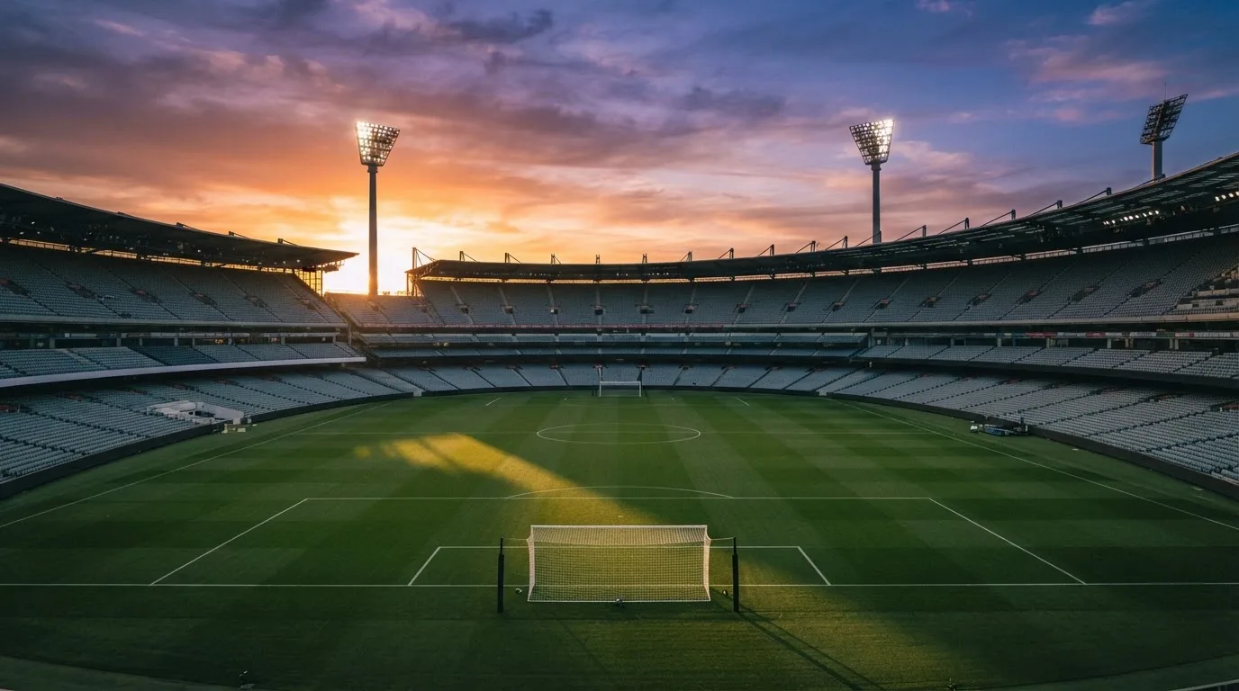 Un estadio de fútbol vacío con torres de iluminación al atardecer