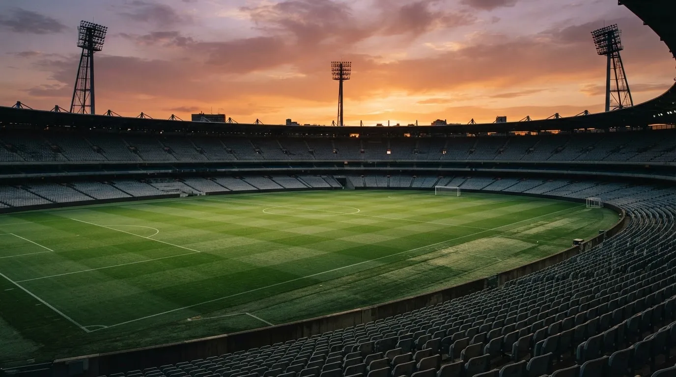 Un estadio de fútbol vacío con torres de iluminación al atardecer