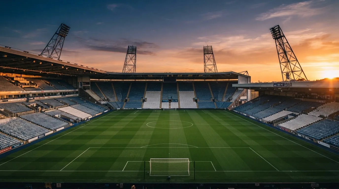 Un estadio de fútbol vacío con torres de iluminación al atardecer