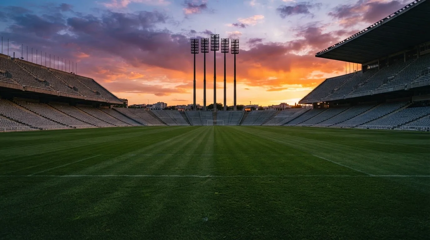 Un estadio de fútbol vacío con torres de iluminación al atardecer