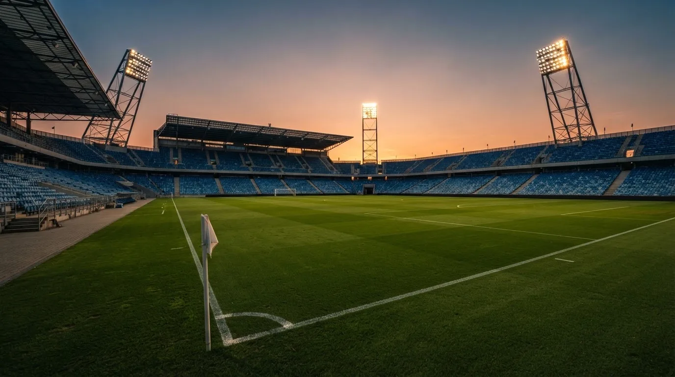 Un estadio de fútbol vacío con torres de iluminación al atardecer