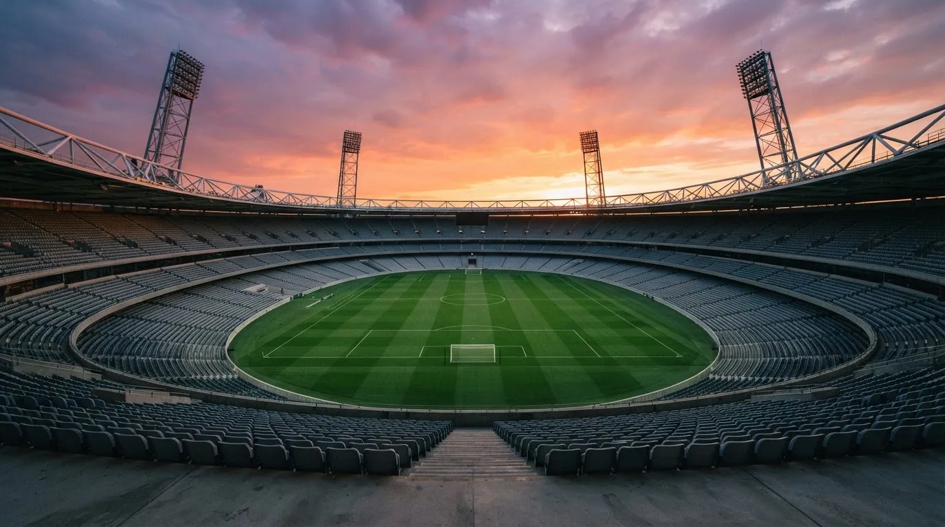 Un estadio de fútbol vacío con torres de iluminación al atardecer