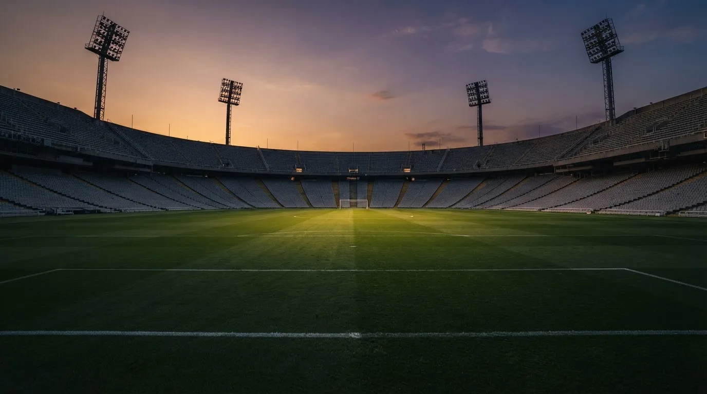 Un estadio de fútbol vacío con torres de iluminación al atardecer