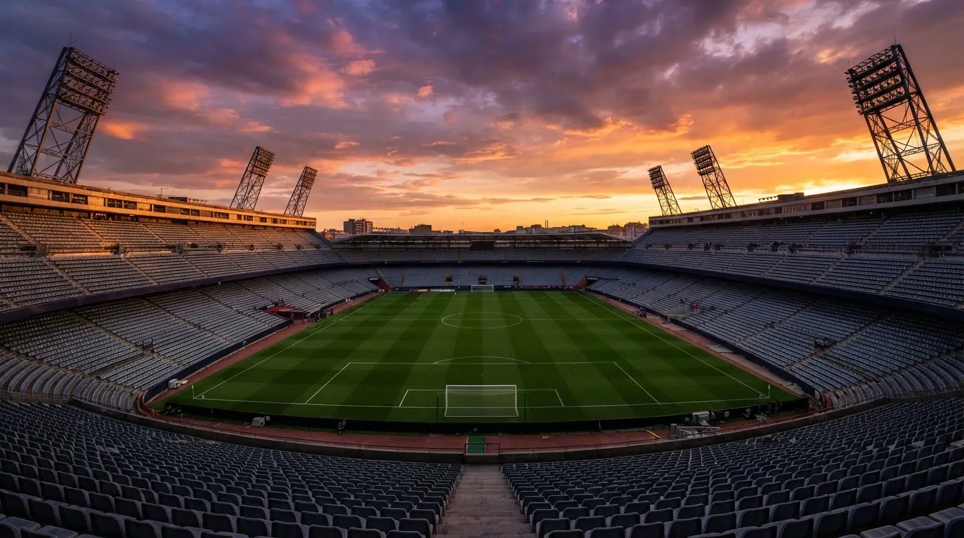 Un estadio de fútbol vacío con torres de iluminación al atardecer