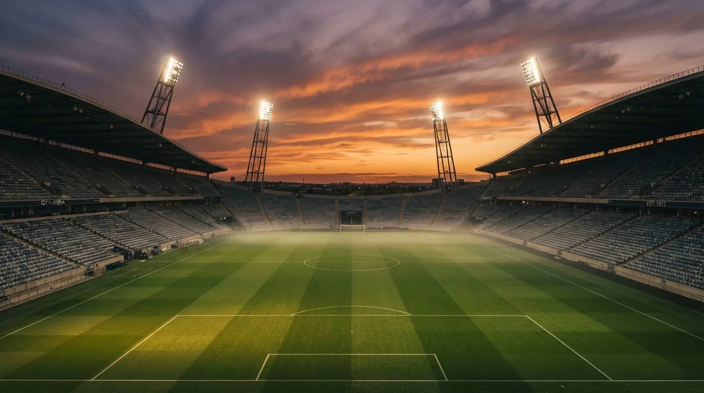 Un estadio de fútbol vacío con torres de iluminación al atardecer