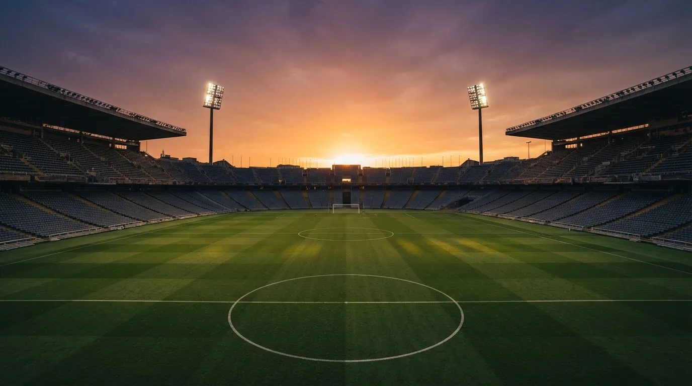 Un estadio de fútbol vacío con torres de iluminación al atardecer