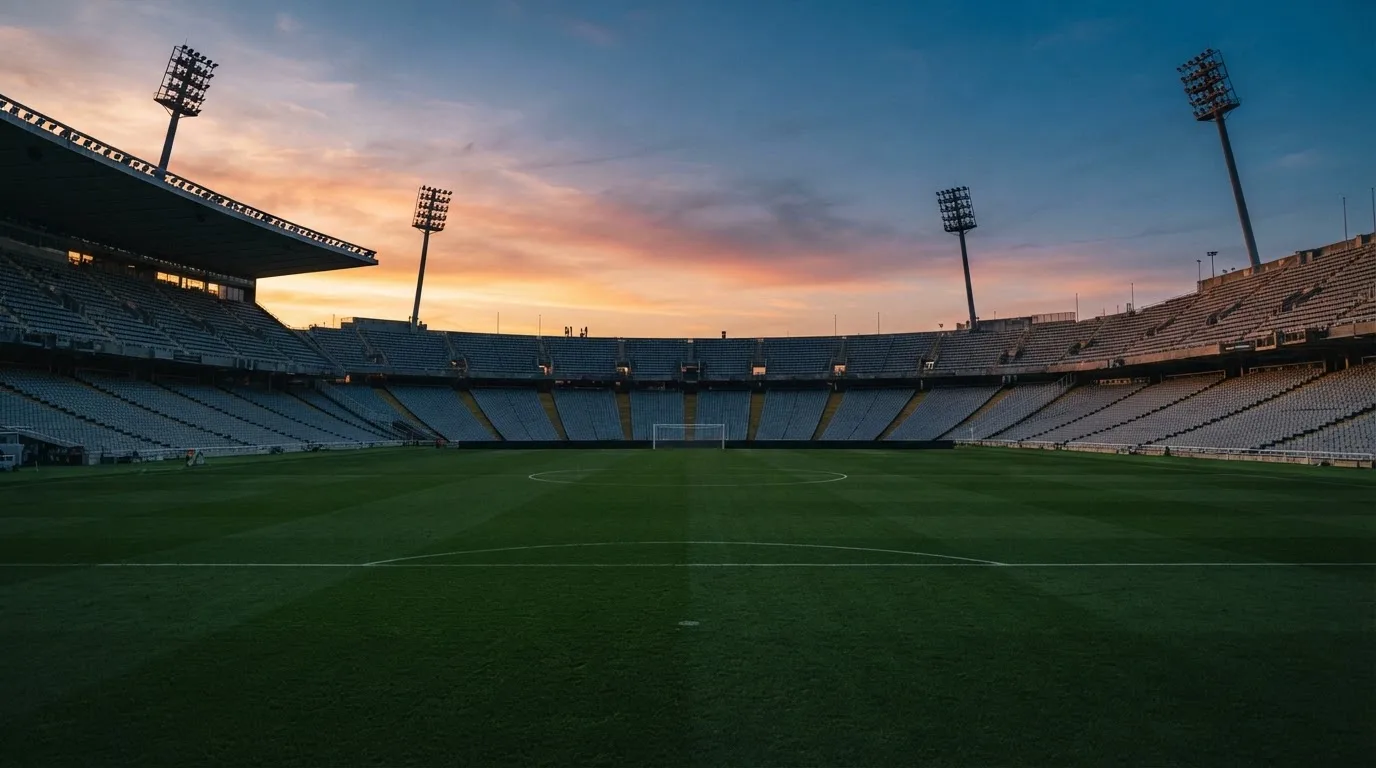Un estadio de fútbol vacío con torres de iluminación al atardecer