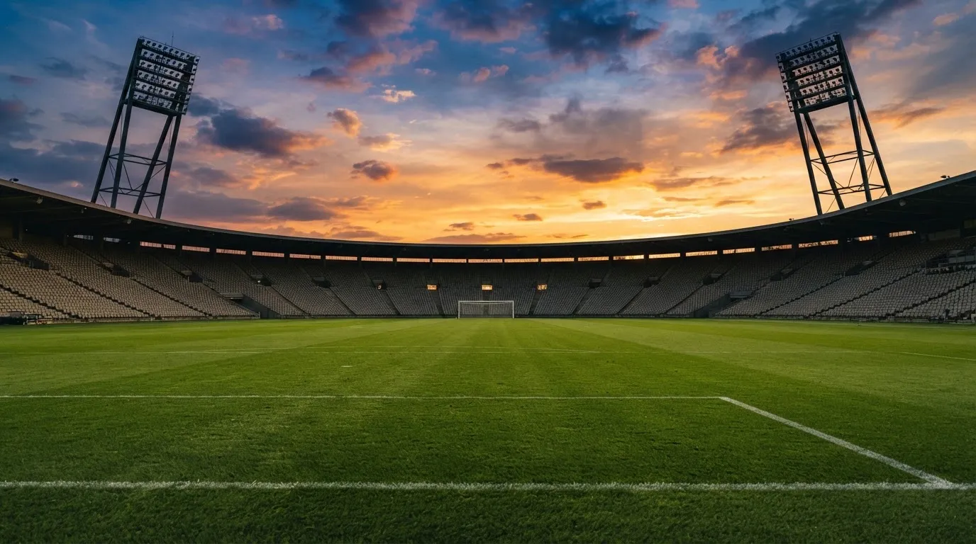 Un estadio de fútbol vacío con torres de iluminación al atardecer