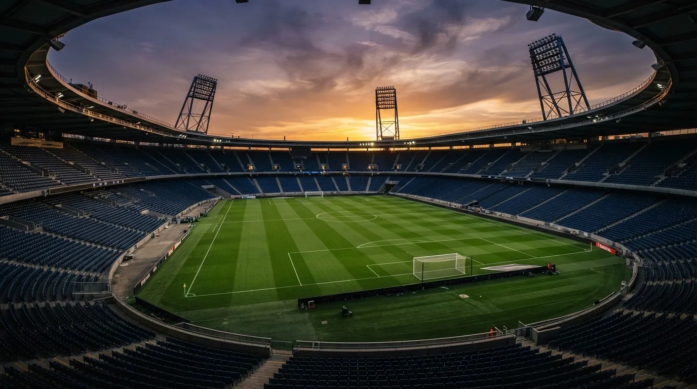 Un estadio de fútbol vacío con torres de iluminación al atardecer